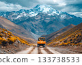 Large construction truck driving along a dirt mountain road with dramatic peaks 133738533