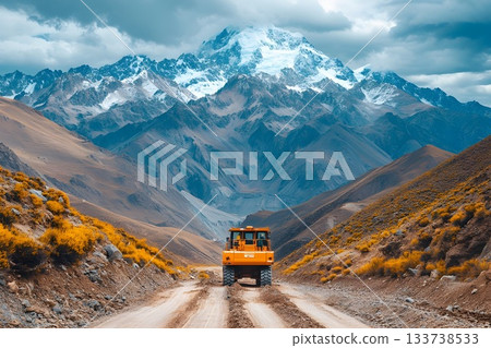 Large construction truck driving along a dirt mountain road with dramatic peaks 133738533