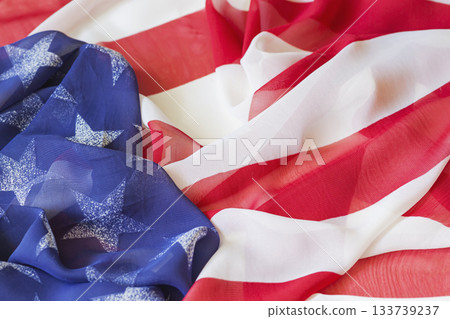 Close-up of American flag fabric with soft folds showing stars and stripes. Independence Day. Concept of freedom, unity, celebration of American spirit, patriotism, national pride Close-up of American flag fabric with soft folds showing stars and stripes. Independence Day. Concept of freedom, unity, celebration of American spirit, patriotism, national pride 133739237
