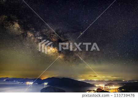 Starry sky of the Setouchi in early spring: Night view of the port town and the Milky Way over the beautiful islands Starry sky of the Setouchi in early spring: Night view of the port town and the Milky Way over the beautiful islands 133739476
