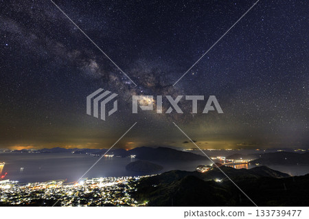 Starry sky of the Setouchi in early spring: Night view of the port town and the Milky Way over the beautiful islands Starry sky of the Setouchi in early spring: Night view of the port town and the Milky Way over the beautiful islands 133739477