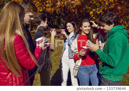 Happy friends having fun standing together with drinks in park Happy friends having fun standing together with drinks in park 133739646