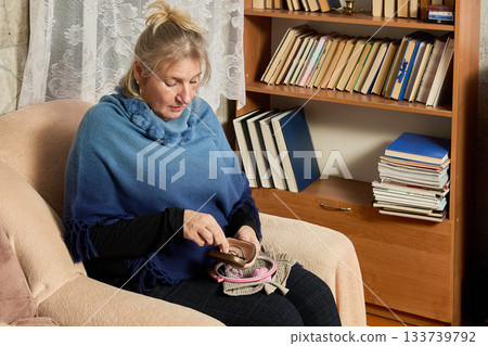Presbyopia makes woman over 50 take reading glasses before sitting to embroider in hoop. 133739792
