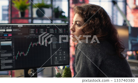 Businesswoman studies financial charts using stock market visualization tools. Digital trading platform provides economic data, forex analysis and price trends for investment planning. Camera B. Businesswoman studies financial charts using stock market visualization tools. Digital trading platform provides economic data, forex analysis and price trends for investment planning. Camera B. 133740380