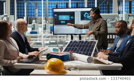 Engineering team in photovoltaics plant improving solar cells efficiency. Solar panels factory research and development department staff members working on clean energy solutions, camera A 133740401