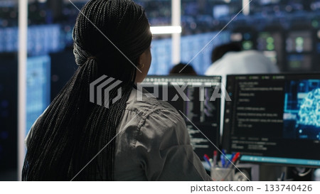 Data center programmer using artificial intelligence deep learning models to configure infrastructure. IT staff member works on AI programming language in server room, optimizing system, camera B Data center programmer using artificial intelligence deep learning models to configure infrastructure. IT staff member works on AI programming language in server room, optimizing system, camera B 133740426