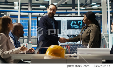 Photovoltaics plant researchers doing meeting, looking at monitor, evaluating solar cells to improve energy production. Experts optimizing factory equipment for better energy absorption, camera B 133740443