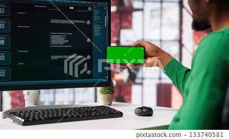 Young man using AI chatbot to generate real time responses next to mockup display, power of artificial intelligence. Smart automation simplifying online communication and problem solving. Camera A. 133740581