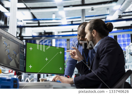 Solar tech workforce reviews diagnostics on pc next to mockup, supporting clean smart energy production and manufacturing process evolution. Working on sustainable solutions at the plant. 133740626