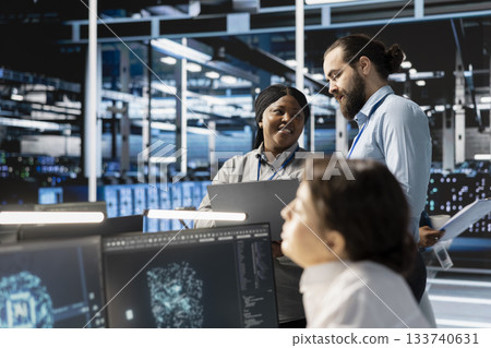 Team of engineers in data center integrating AI driven automation tools, doing maintenance. Teamworking colleagues in server room using artificial intelligence machine learning models 133740631