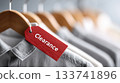 Close up of a bright red clearance tag attached to stylish clothing on hangers, showcasing retail fashion and promotional sales opportunities 133741896