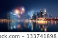 City skyline illuminated by colorful fireworks reflecting on calm water, creating a vibrant and festive atmosphere at night with copy space 133741898
