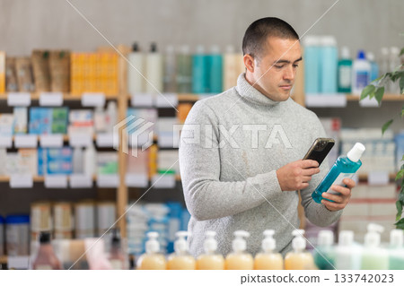 Young man scanning qr code of mouthwash Young man scanning qr code of mouthwash 133742023