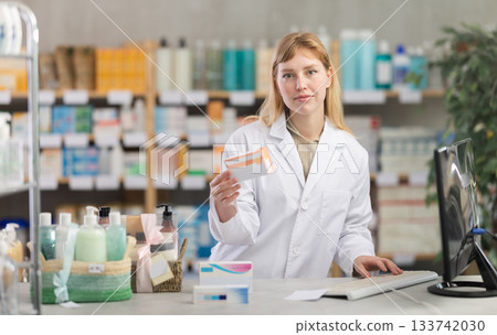 Female pharmacist working at computer offering pills Female pharmacist working at computer offering pills 133742030