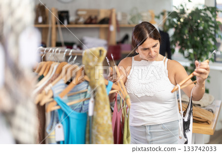 Latin woman customer turn over and choose something summer cloth in store, 133742033