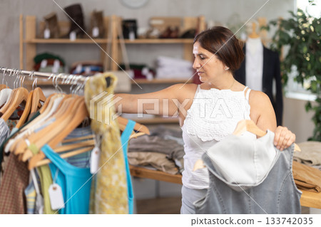 Latin woman customer turn over and choose something summer cloth in store, 133742035