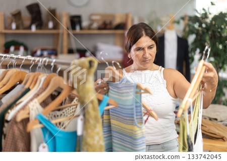 Latin woman customer turn over and choose something summer cloth in store, 133742045