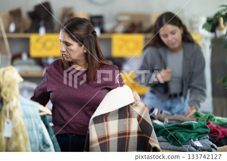 Adult woman chooses plaid jacket in clothing store 133742127