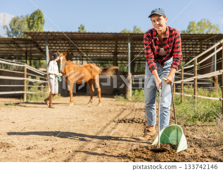 Young woman cleaning horse pen 133742146