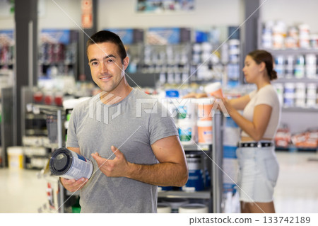 Smiling man standing in hardware store with can of paint Smiling man standing in hardware store with can of paint 133742189