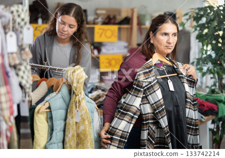 Selective Latina woman choosing something for autumn-winter in clothing store Selective Latina woman choosing something for autumn-winter in clothing store 133742214