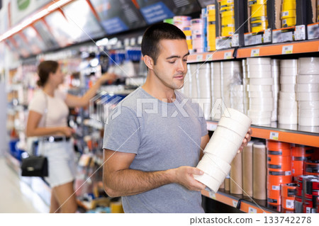 Man buy sticky adhesive tape in construction store for carrying out internal finishing work 133742278