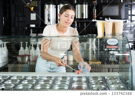 Positive saleswoman inviting to try aromatic bubble tea Positive saleswoman inviting to try aromatic bubble tea 133742388