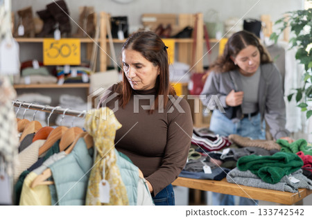 Adult woman choosing winter clothes in store Adult woman choosing winter clothes in store 133742542