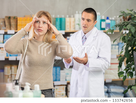 Woman with headache on the background of a pharmacist Woman with headache on the background of a pharmacist 133742656