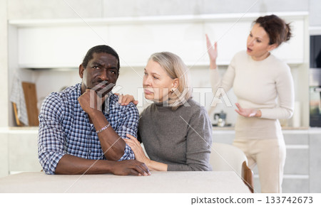 Old woman trying to calm angry man while middle-aged woman quarreling to him 133742673