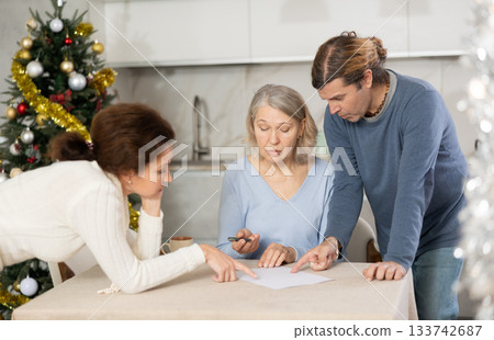 Married couple helps elderly mother write testament in kitchen at christmas 133742687
