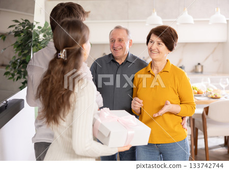 Happy girl introducing boyfriend to parents and giving gifts, coming family celebration Happy girl introducing boyfriend to parents and giving gifts, coming family celebration 133742744
