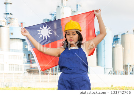 Portrait of positive girl in construction overalls with the Taiwan flag on the background of modern factory 133742766