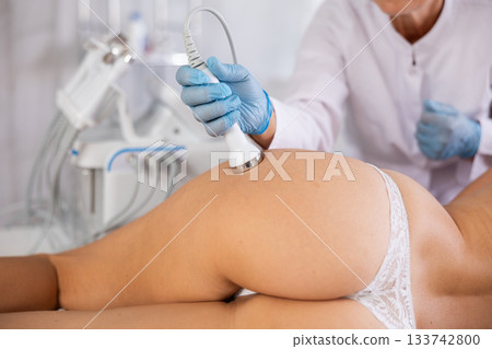 Young woman undergoing high frequency ultrasound procedure on buttocks Young woman undergoing high frequency ultrasound procedure on buttocks 133742800