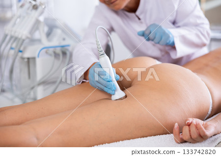 Anti aging thigh hardware therapy procedure for young female client in clinic of aesthetic medicine 133742820