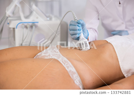 Hardware anti-cellulite procedure on belly of young woman in beauty clinic Hardware anti-cellulite procedure on belly of young woman in beauty clinic 133742881