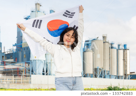 Happy young woman with flag of South Korea against background of factory Happy young woman with flag of South Korea against background of factory 133742883