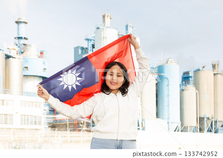 Happy young woman with flag of Taiwan against background of factory Happy young woman with flag of Taiwan against background of factory 133742952