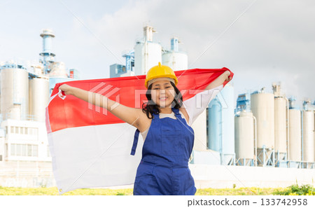 Happy young woman with helmet holding big flag of Indonesia 133742958