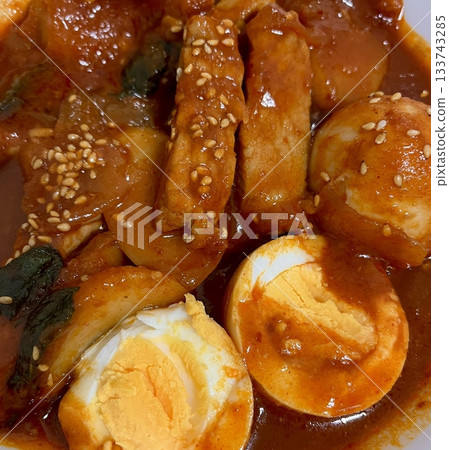 Spicy Korean tteokbokki with chewy rice cakes in a vibrant red sauce, topped with sesame seeds and green onions. A popular street food known for its addictive flavor and satisfying texture. Spicy Korean tteokbokki with chewy rice cakes in a vibrant red sauce, topped with sesame seeds and green onions. A popular street food known for its addictive flavor and satisfying texture. 133743285