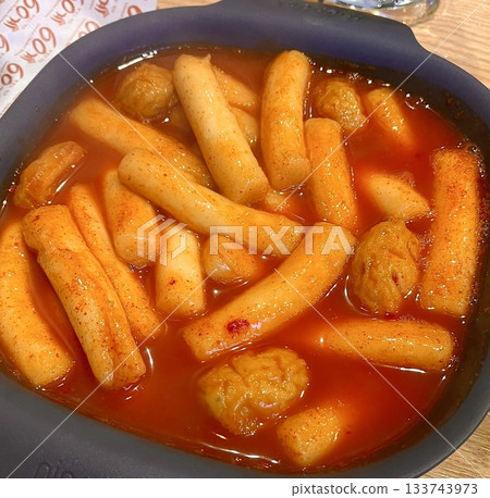 Spicy Korean tteokbokki with chewy rice cakes in a vibrant red sauce, topped with sesame seeds and green onions. A popular street food known for its addictive flavor and satisfying texture. 133743973