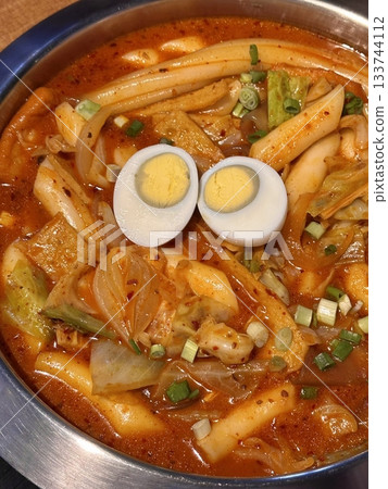 Spicy Korean tteokbokki with chewy rice cakes in a vibrant red sauce, topped with sesame seeds and green onions. A popular street food known for its addictive flavor and satisfying texture. 133744112