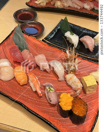 An assortment of fresh sushi, artfully arranged with a variety of toppings and vibrant colors. This traditional Japanese dish combines vinegared rice, seafood, and vegetables for an experience. An assortment of fresh sushi, artfully arranged with a variety of toppings and vibrant colors. This traditional Japanese dish combines vinegared rice, seafood, and vegetables for an experience. 133744492