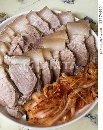 Suyuk, a traditional Korean dish of boiled pork slices, tender and juicy, often served with salted shrimp sauce, garlic, and ssamjang. Perfect for wrapping in lettuce for a flavorful, balanced bite. 133744494