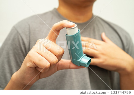 Asthma and chronic obstructive pulmonary disease COPD, Asian young man using metered dose inhaler MDI. Asthma and chronic obstructive pulmonary disease COPD, Asian young man using metered dose inhaler MDI. 133744799