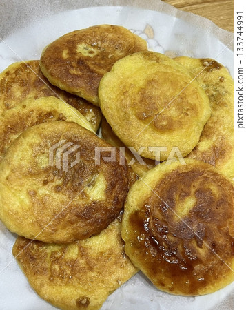 Golden, crispy Hotteok, a popular Korean street snack filled with gooey, sweet syrup, brown sugar, and nuts. Perfectly warm and satisfying with each chewy bite. 133744991