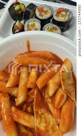Spicy Korean tteokbokki with chewy rice cakes in a vibrant red sauce, topped with sesame seeds and green onions. A popular street food known for its addictive flavor and satisfying texture. 133744995