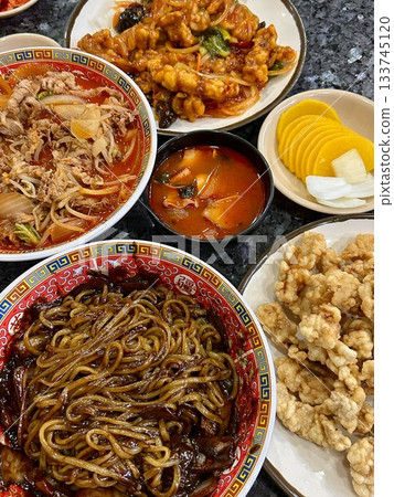 Jjampong and Jajangmyeon are two iconic Korean-Chinese noodle dishes. Jjampong is a spicy seafood noodle soup with vegetables, while Jajangmyeon features noodles topped with a savory black bean sauce. 133745120