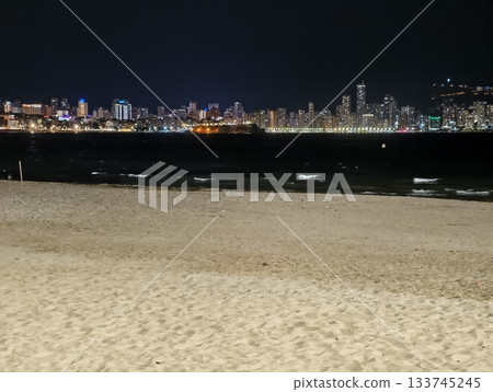silent sandy shoreline facing distant city lights gentle surf empty foreground and soft nocturnal silent sandy shoreline facing distant city lights gentle surf empty foreground and soft nocturnal 133745245