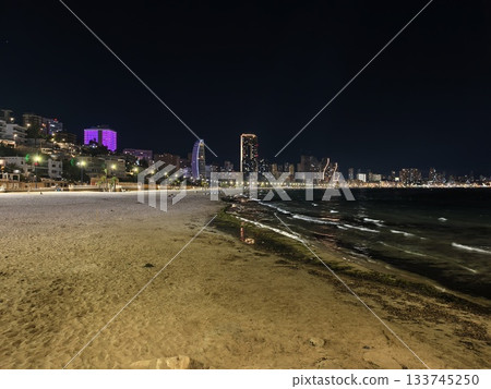 illuminated coastal promenade at night, nighttime bay with glowing promenade and distant skyscrapers 133745250